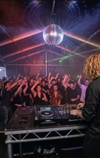 DJ GΛLE performing for a packed crowd under a disco ball